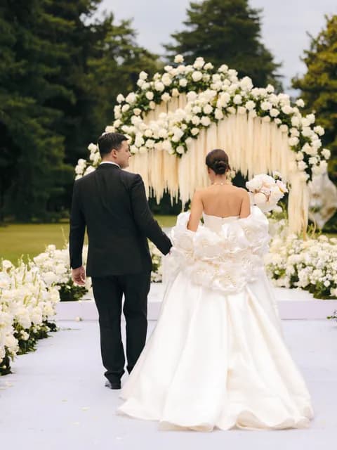 A couple at their floral ceremony arch